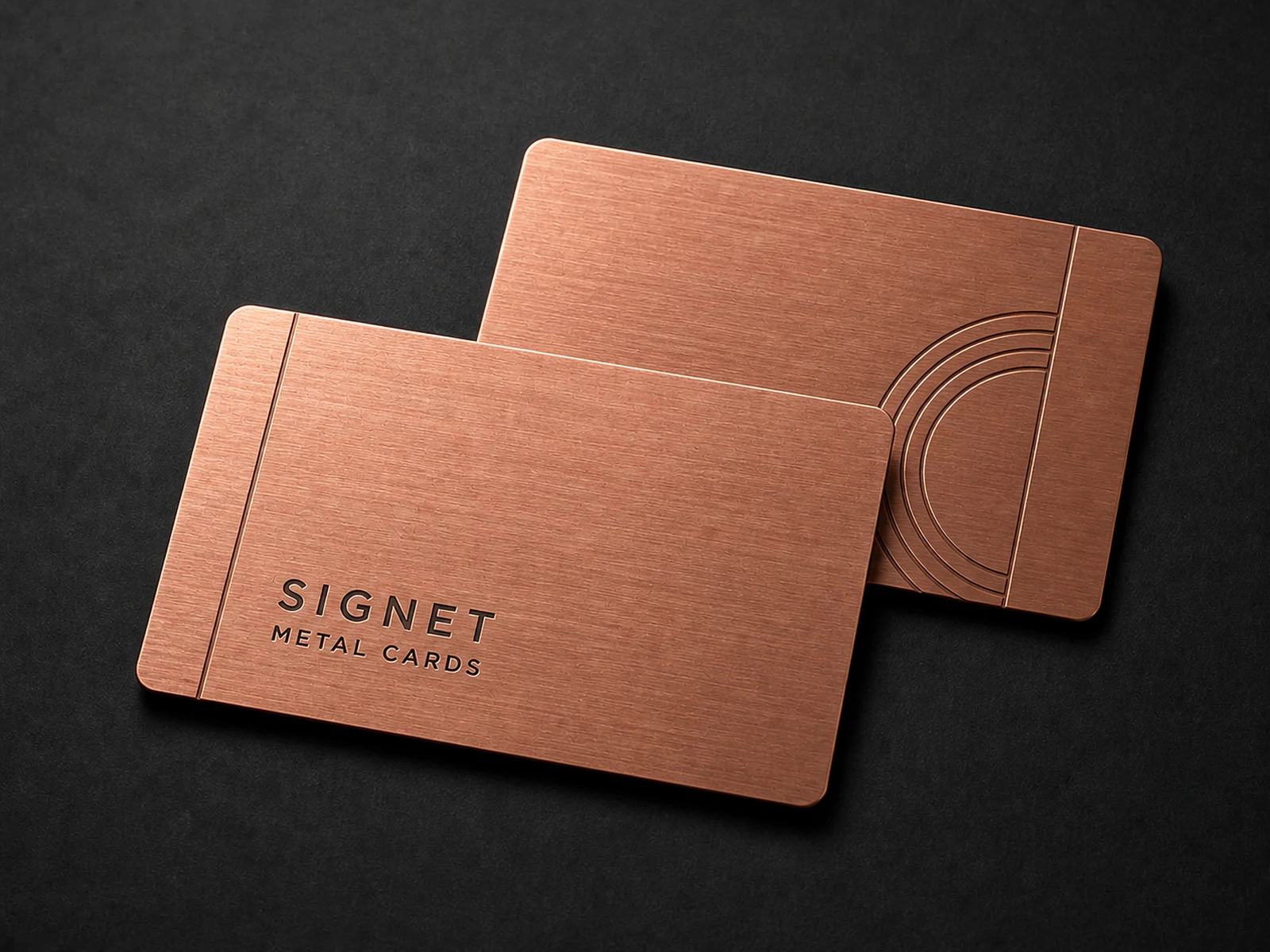 Two warm copper metal business cards with a directional brushed finish