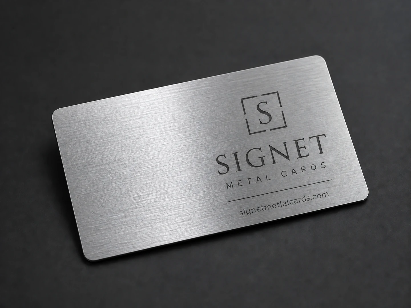 Silver brushed metal business card with visible directional grain and Signet design