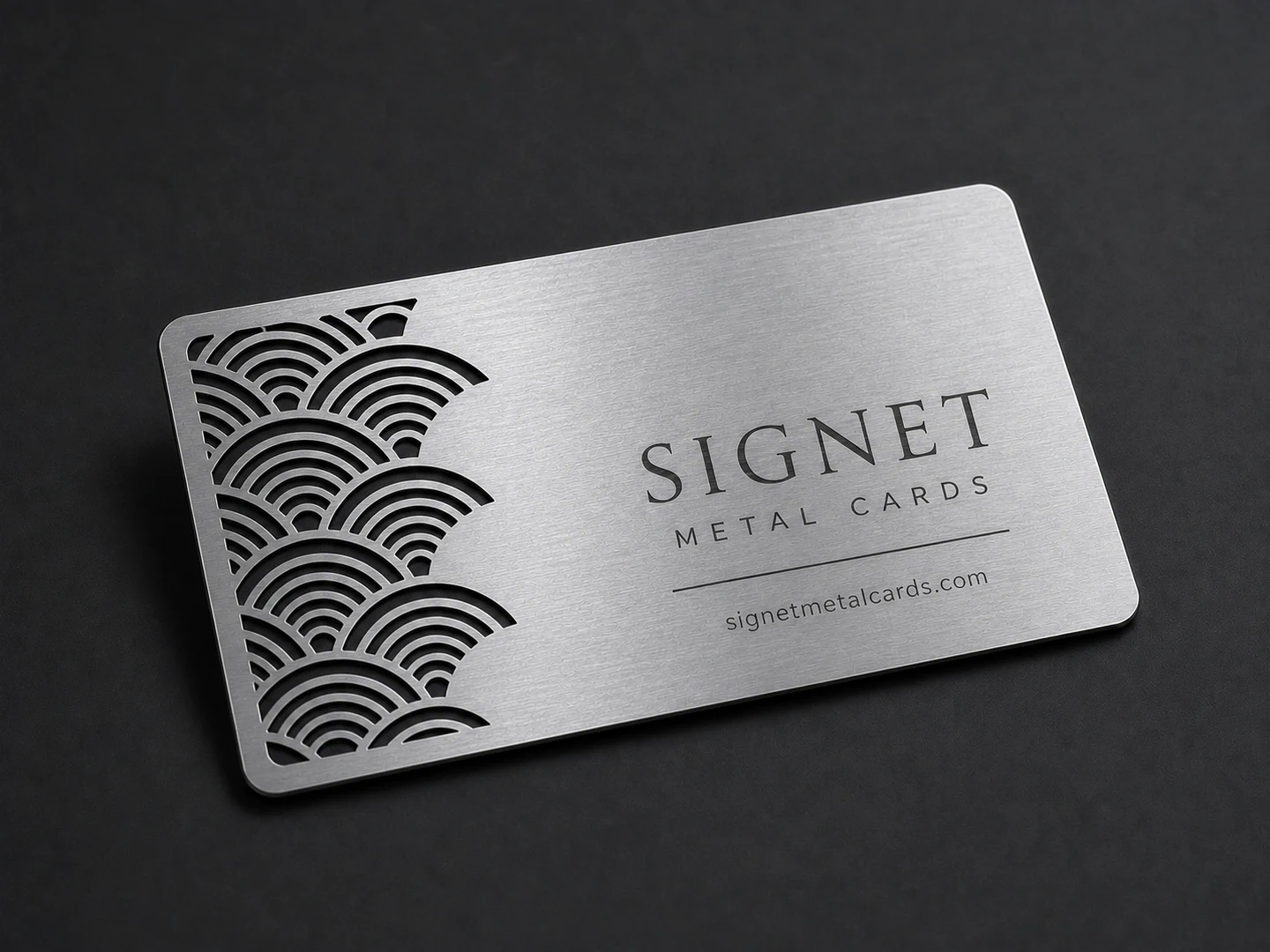 Silver laser-cut metal business card with localized wave-pattern openings and Signet design