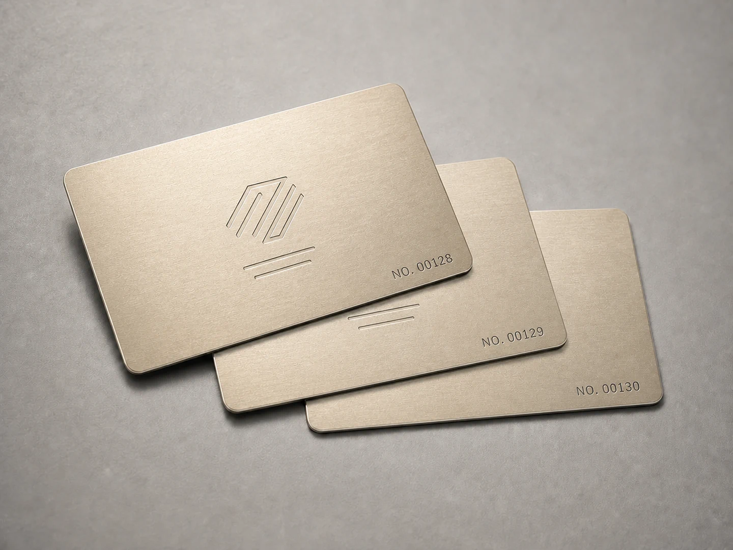 Three champagne gold personalized metal business cards with unique serial numbers in the lower-right corner